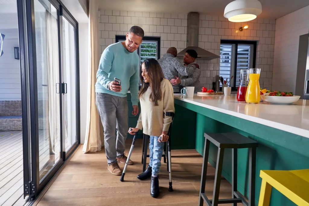 Support worker with disabled woman in kitchen looking at mobile phone