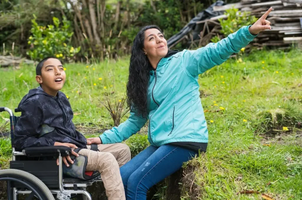 Support worker with disabled boy in wheelchair outside